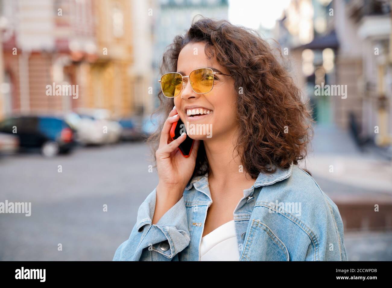 Multiethnische junge Frau, die mit Freunden auf dem Handy im Freien spricht. Stockfoto