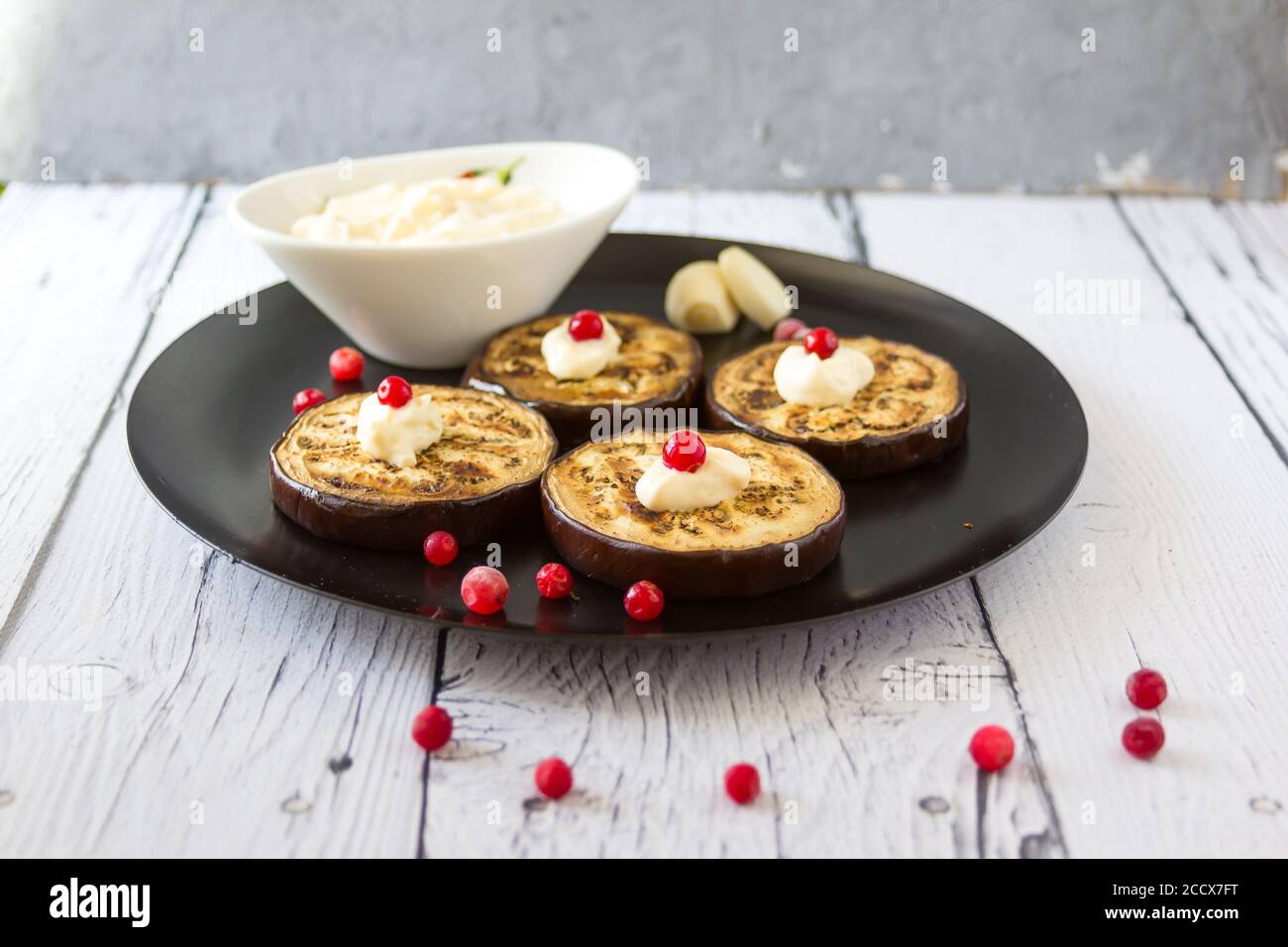 Gebratene Aubergine mit Knoblauchsauce und Preiselbeeren mit Basilikumblättern Stockfoto