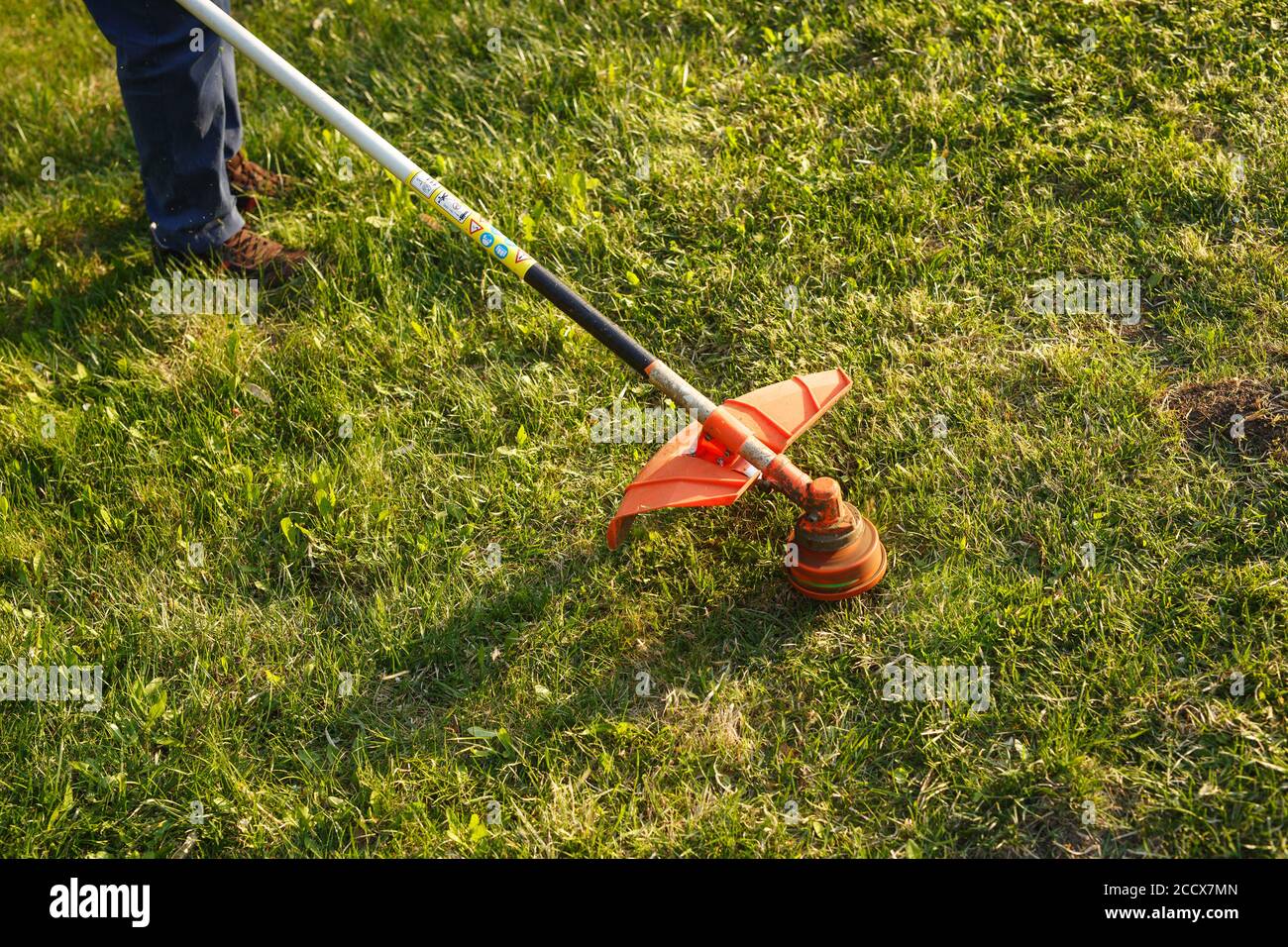 Mähen Trimmer - Arbeiter Schneiden von Gras im grünen Hof bei Sonnenuntergang. Stockfoto