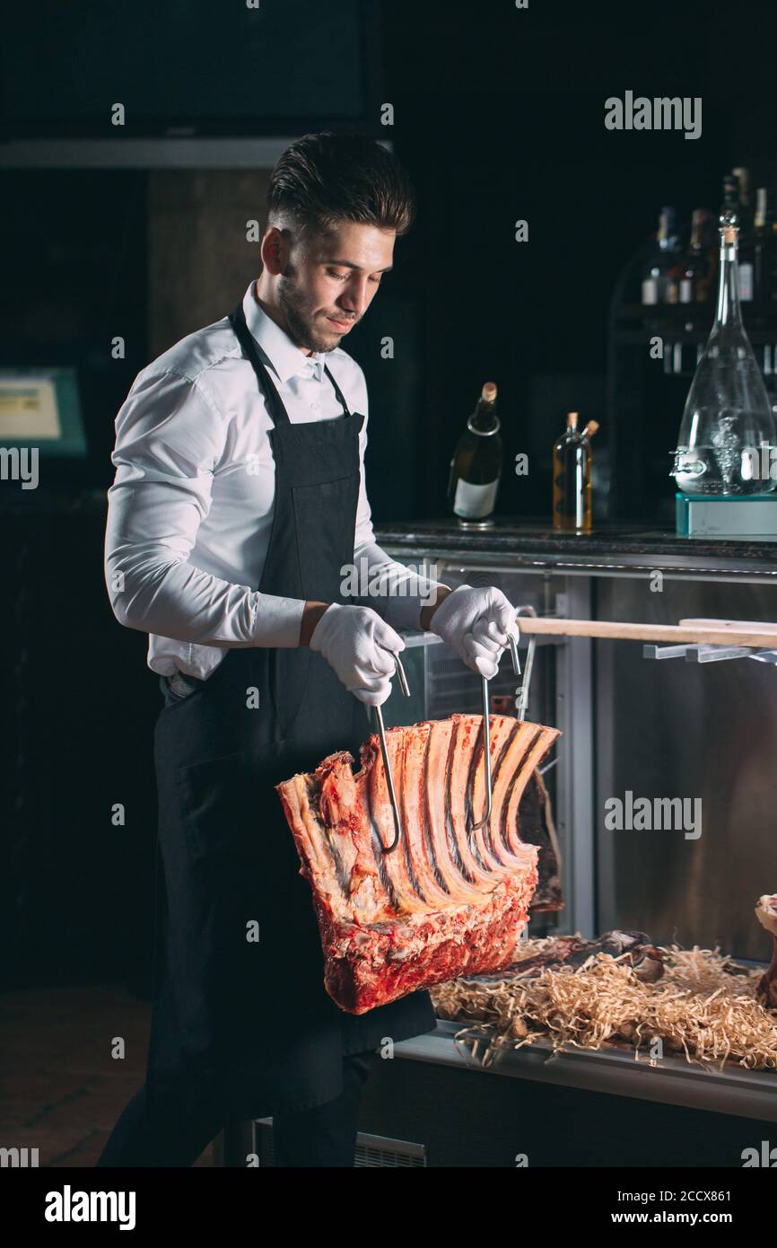 Der Kellner oder Koch bekommt trockenes Fleisch im Kühlschrank. Stockfoto