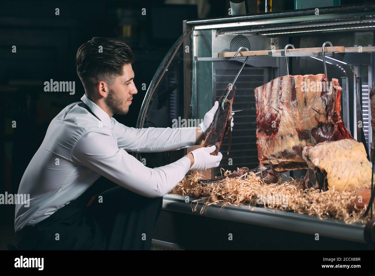 Der Kellner oder Koch bekommt trockenes Fleisch im Kühlschrank. Stockfoto