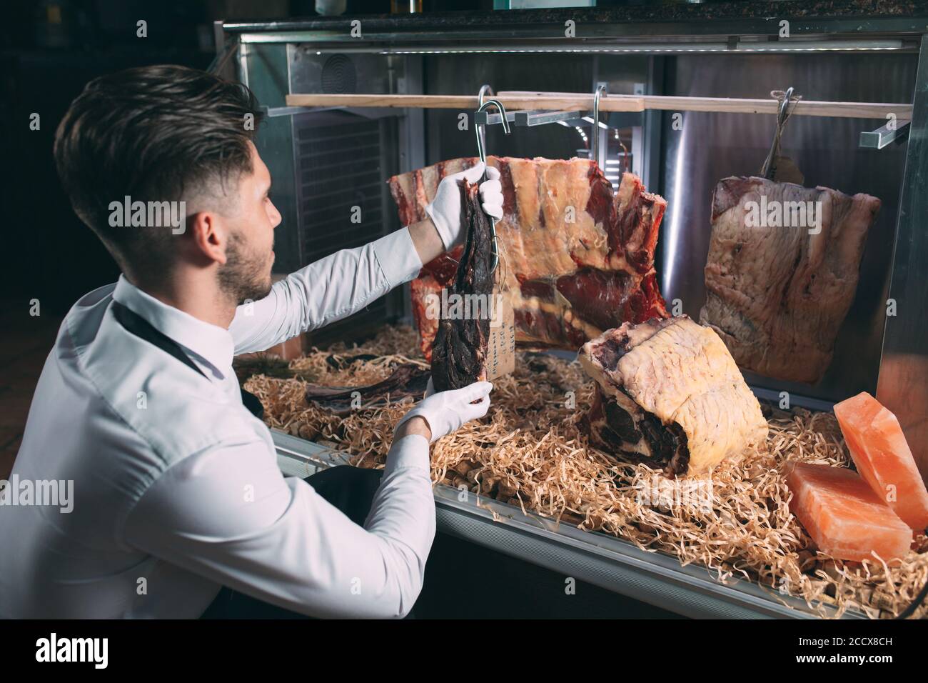 Der Kellner oder Koch bekommt trockenes Fleisch im Kühlschrank. Stockfoto