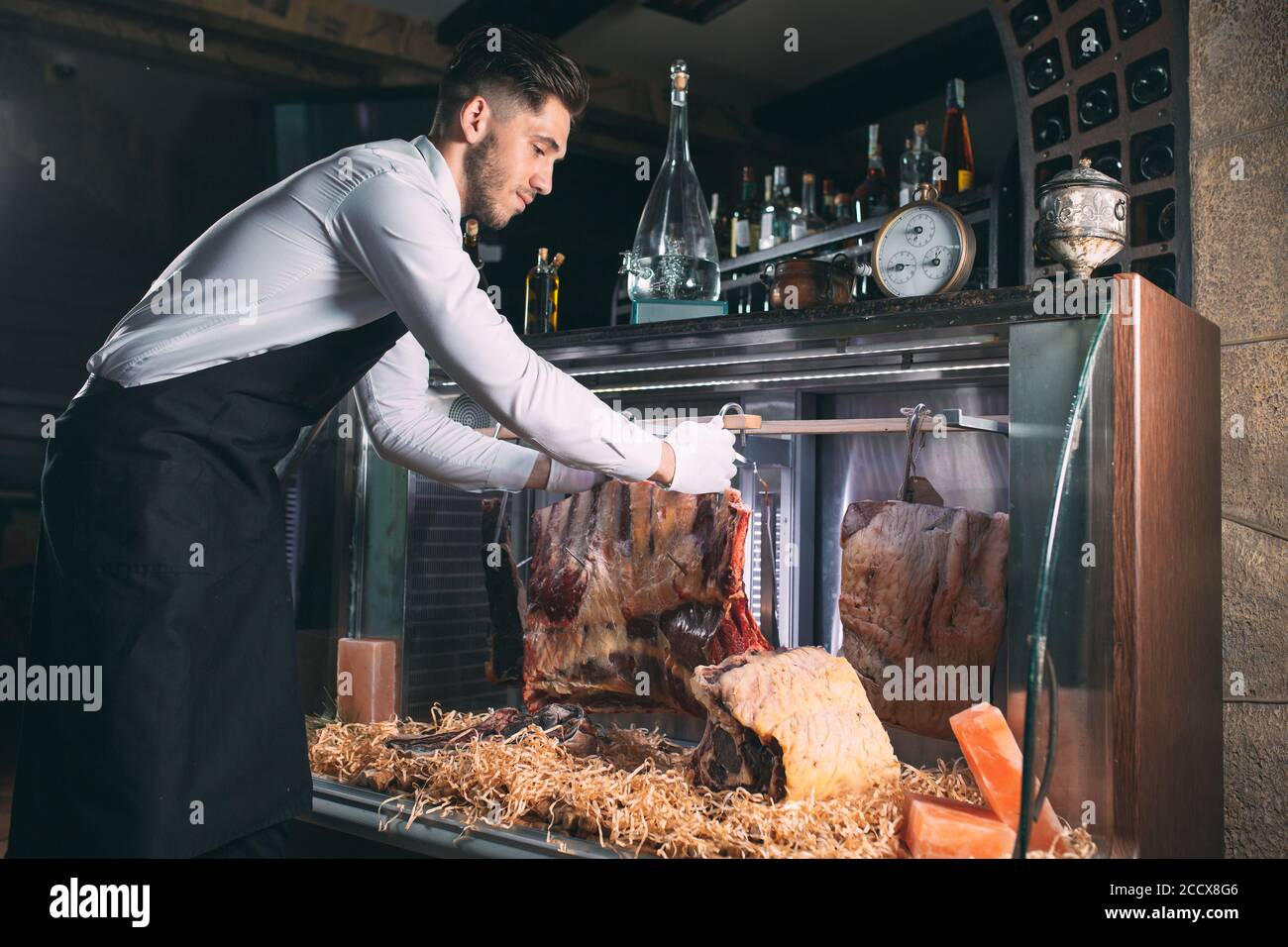 Der Kellner oder Koch bekommt trockenes Fleisch im Kühlschrank. Stockfoto