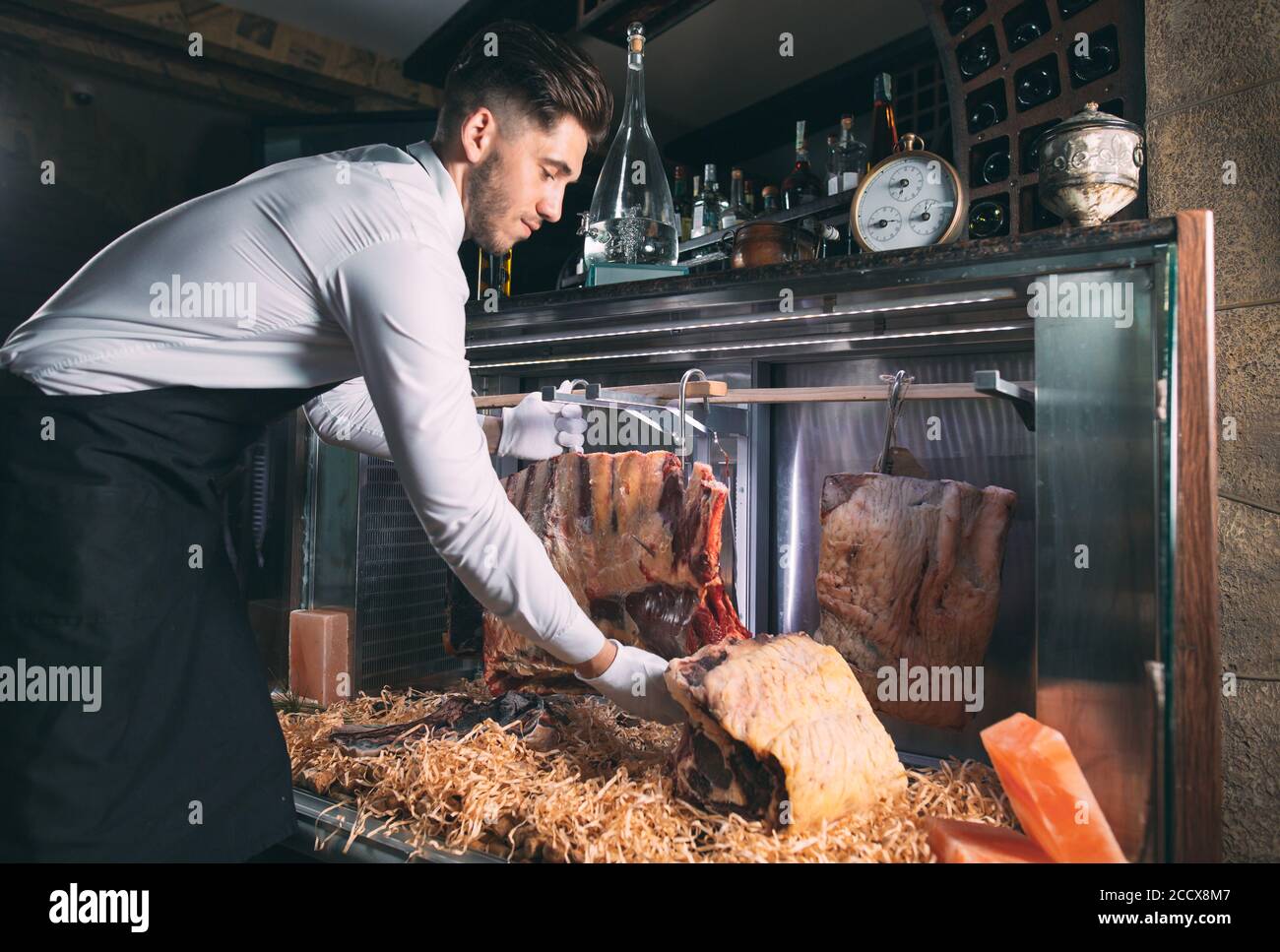 Der Kellner oder Koch bekommt trockenes Fleisch im Kühlschrank. Stockfoto