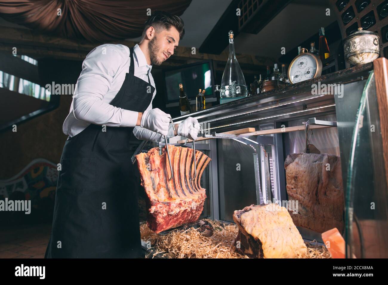 Der Kellner oder Koch bekommt trockenes Fleisch im Kühlschrank. Stockfoto