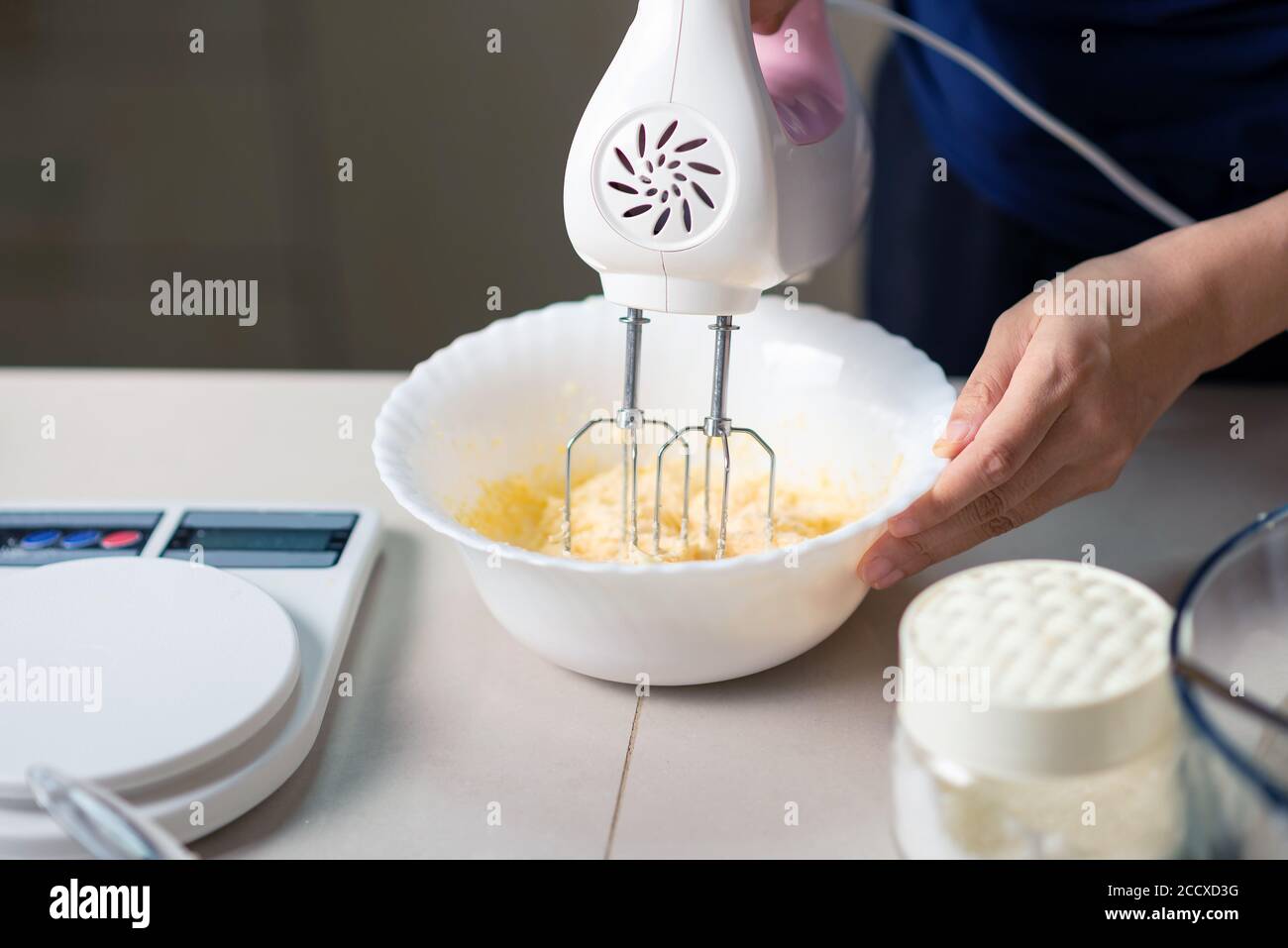 Frau mit elektrischen Mixer Zutaten für Teig von Zucker, geschlagene Eier, Butter und Mehl mischen, während Cookies in der Küche zu Hause Nahaufnahme Stockfotografie