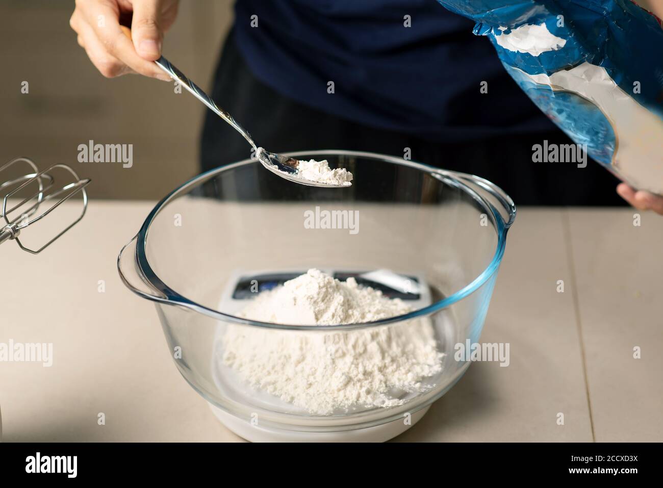 Frau, die Mehl auf einer Küchenwaage misst, während sie Teig macht Zu Hause Stockfoto