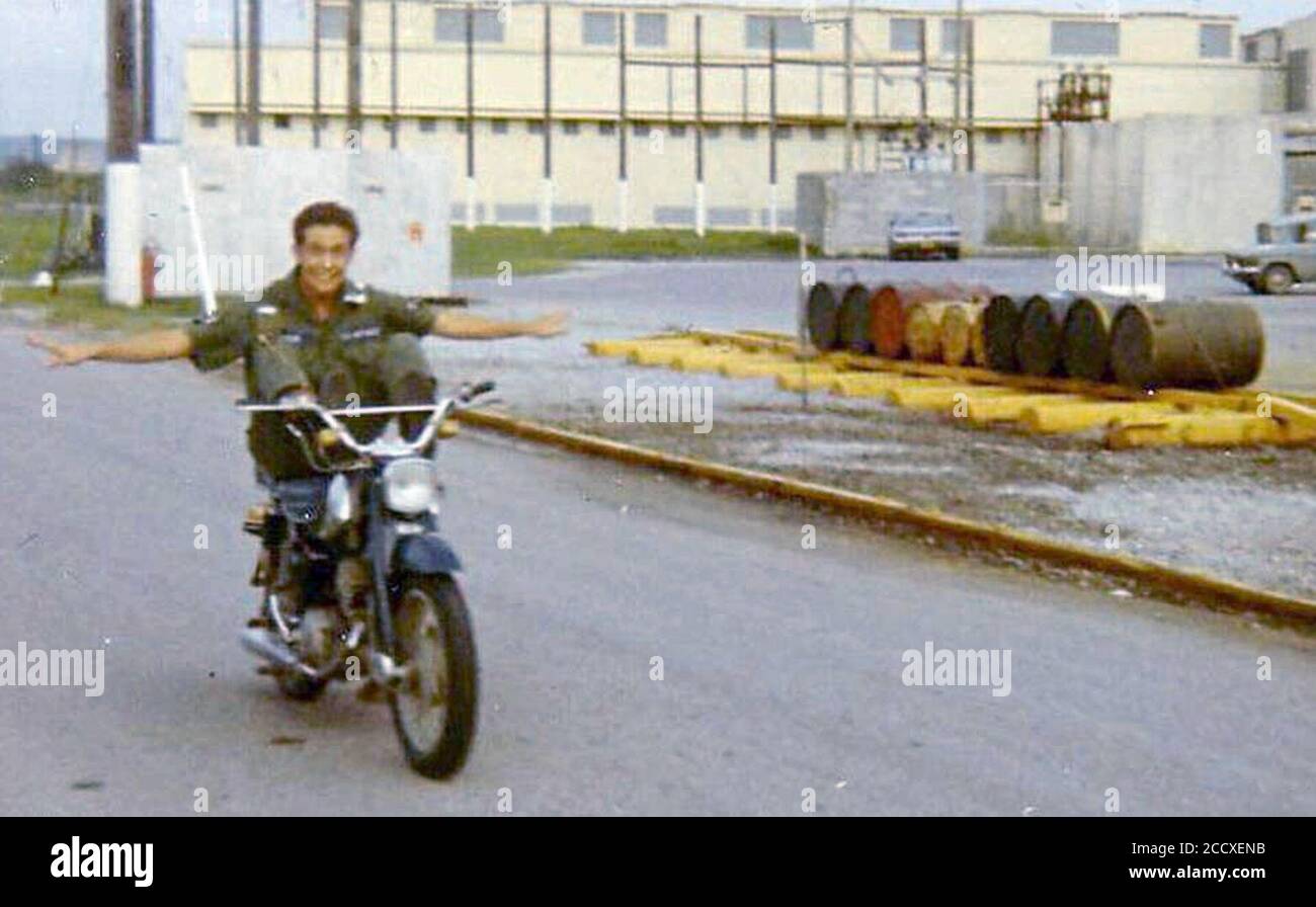 Joe Sipala fährt 1970 neben einem Fass Agent Orange (Dritter von links) auf Okinawa mit seinem Motorrad. Stockfoto