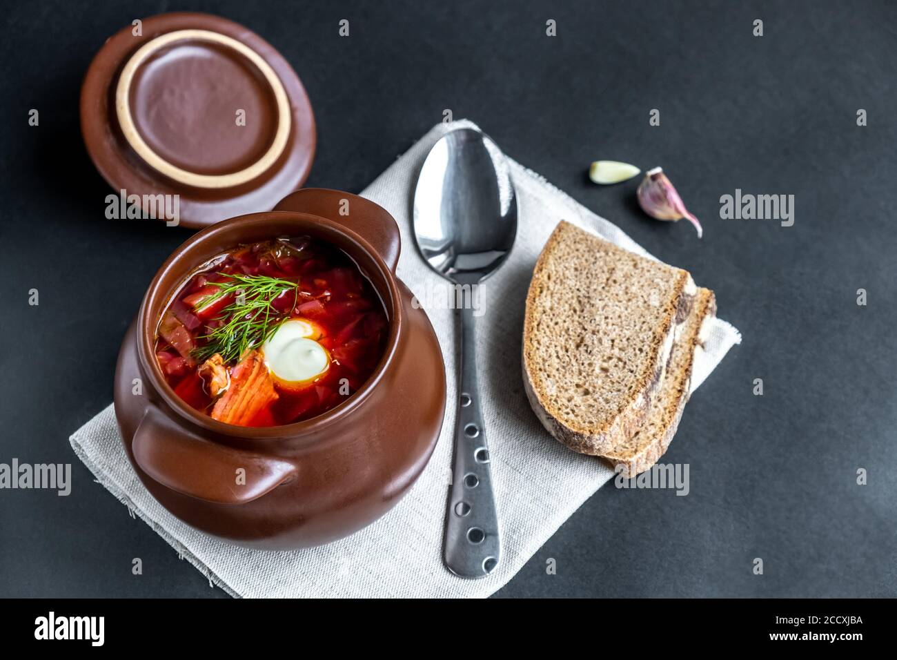 Borscht in einen Topf. Gemüsesuppe mit Fleisch, Sauerrahm und Knoblauch auf dunklem Grund. Traditionelle slawische Küche.Nahaufnahme.selektiver Fokus. Copyspace Stockfoto