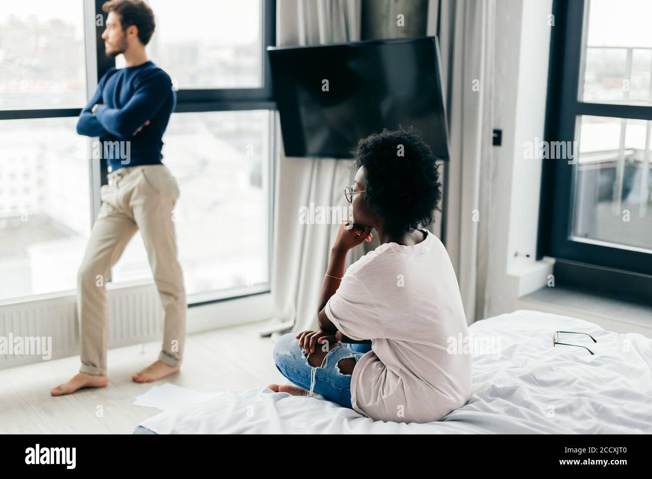 Frustrierte afrikanische Frau, die sich beleidigt und niedergeschlagen fühlt, nachdem sie wusste, dass die Verlobung gescheitert ist. Ihr anmutender Bräutigam von europäischem Aussehen gerecht Stockfoto