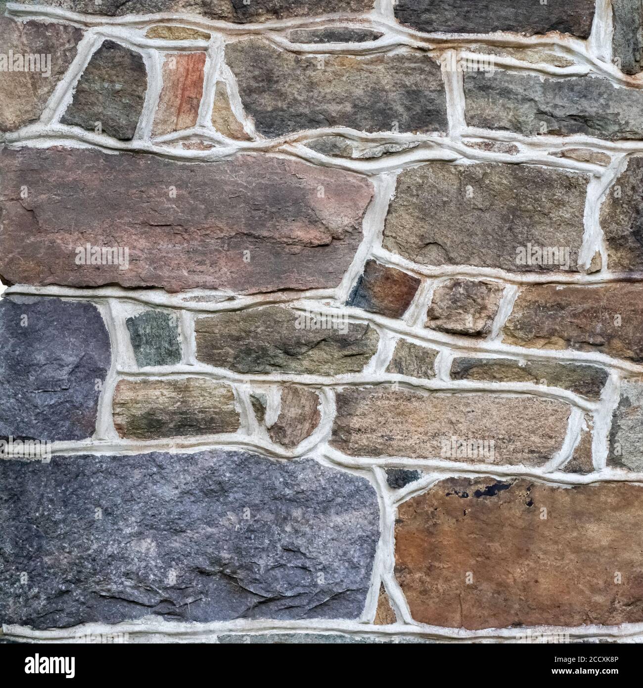 Bunte Feldstein Mauerwerk zeigt künstlerische Stärke und Heft. Altmodische Mörtelarbeit mit bunten Steinen in verschiedenen Formen und Größen. Stockfoto