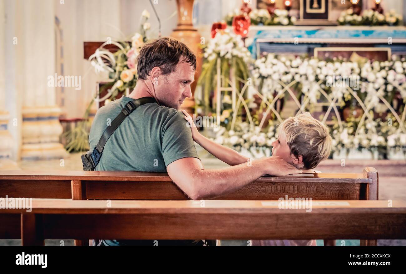 Christian Papa erzählt seinem Sohn biblische Geschichten über Jesus in kirk sitzen. Glaube, Religionsunterricht, moderne Kirche, Vatertag, väterliche Stockfoto