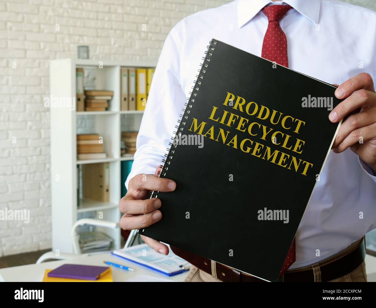 Manager zeigt das PLM-Buch „Product Lifecycle Management“ an. Stockfoto