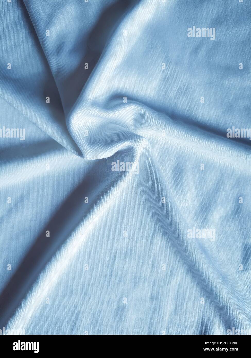 Sternförmige kreisförmige Muster auf Seidenstoff, handgefertigte Faltungen auf Tüchern, elegant blau getönt. Nützlich für Hintergrundbilder. Stockfoto