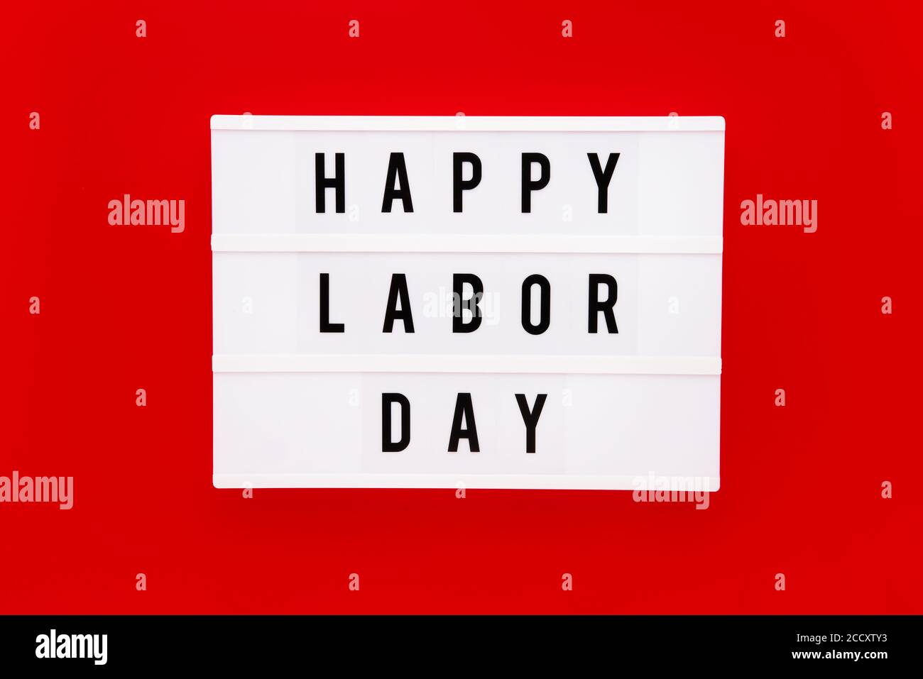 HAPPY LABOR DAY in einem Leuchtkasten auf einem leuchtend roten Hintergrund geschrieben. Labor Day-Konzept Stockfoto
