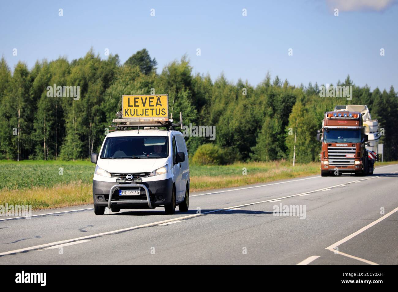 Pilotfahrzeug führt Überlasttransport eines Freizeitbootes auf der Autobahn 10. Tammela, Finnland. 21. August 2020. Stockfoto