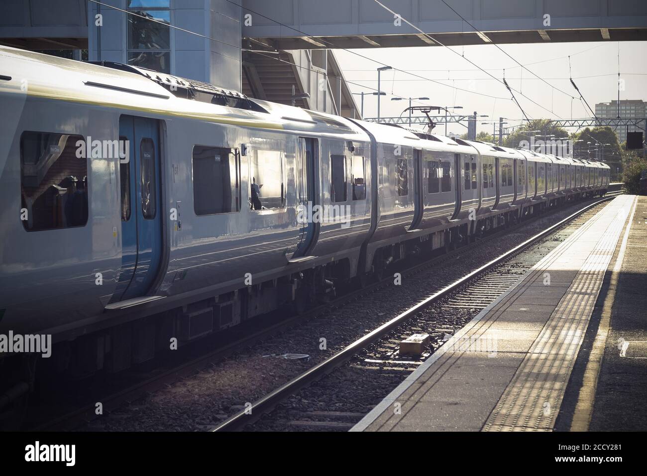 Leerer Bahnsteig, Zug am Bahnhof West Hampstead in London mit launischer Sonneneinstrahlung Stockfoto