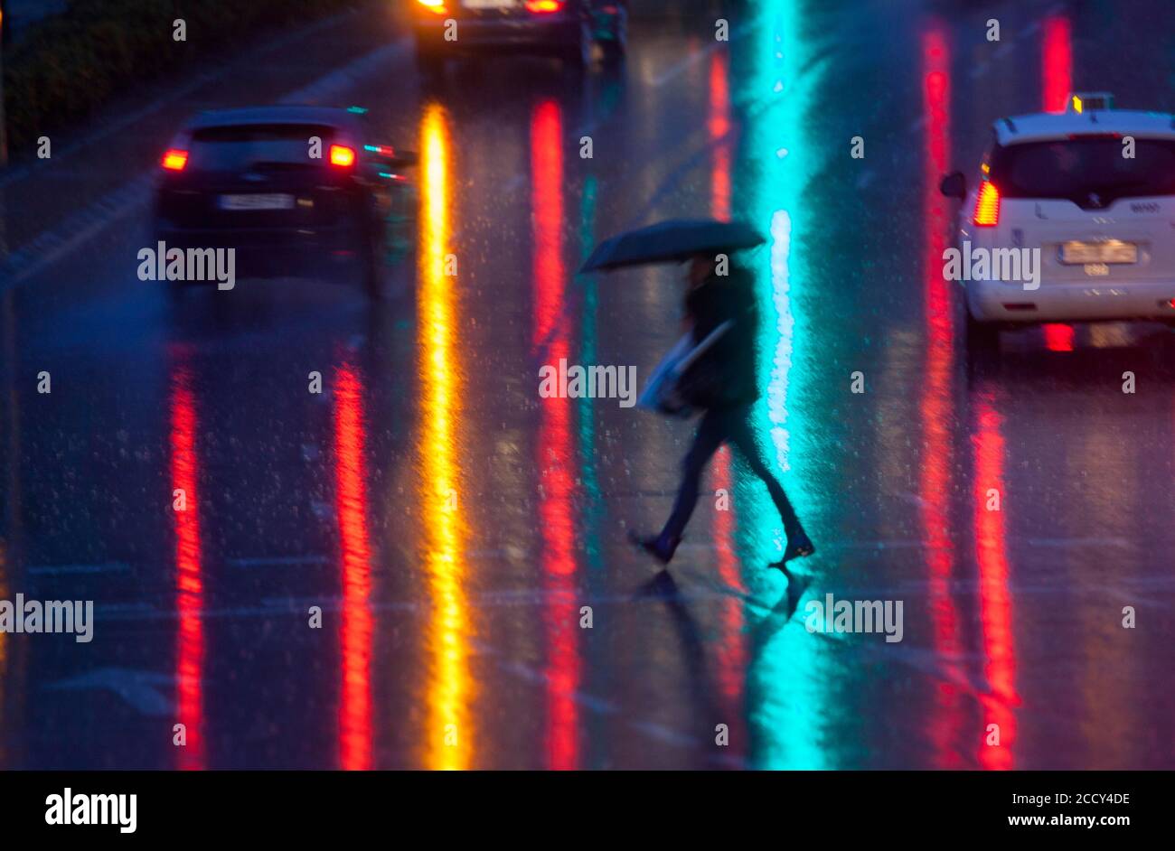 Ein Fußgänger überqueren die nasse Straße mit den Reflexen der Auto Lichter, Madrid gemalt Stockfoto