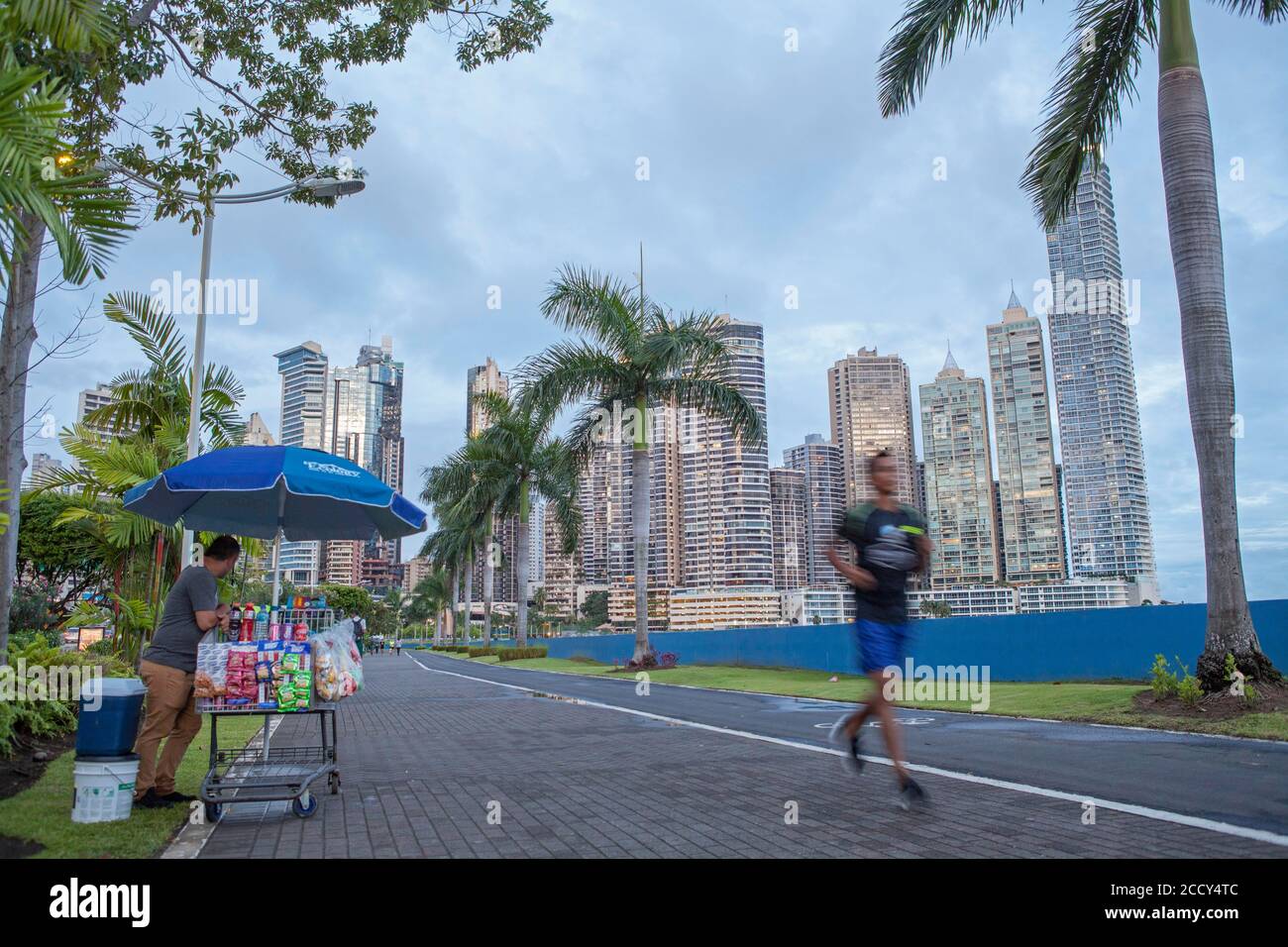Straßenverkäufer und Jogger auf dem Bürgersteig neben Balboa Avenue, Panama City, Panama Stockfoto