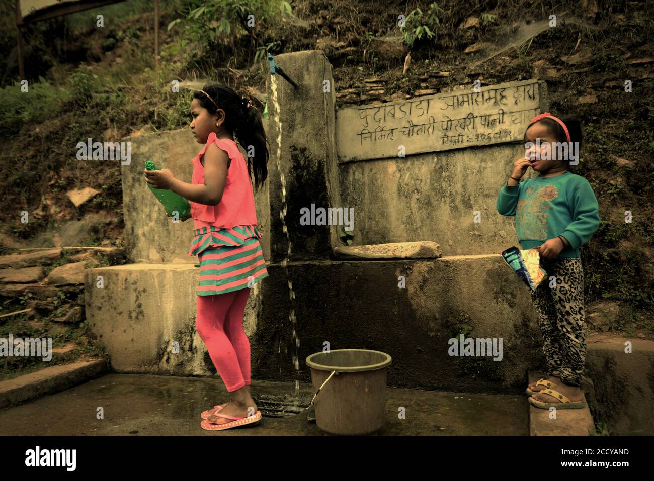 Kinder, die Wasser aus einer kommunalen Wasserquelle in Panchase Region, Provinz Gandaki Pradesh, Nepal. Stockfoto