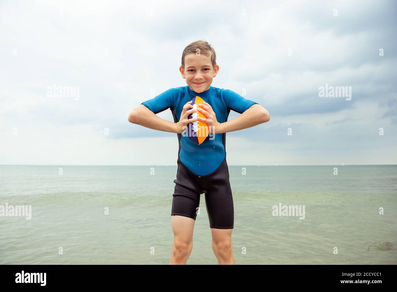 Porträt von schönen Teenager-Jungen spielen mit Ball in Neopren Badeanzug  in der Ostsee Stockfotografie - Alamy