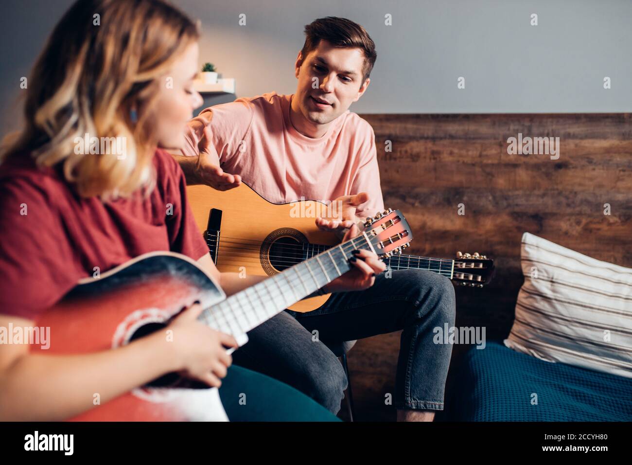 Zwei romantische Menschen in der Liebe sitzen zusammen auf dem Bett, spielen die Gitarre. kaukasische Menschen sitzen zusammen zu Hause Stockfoto