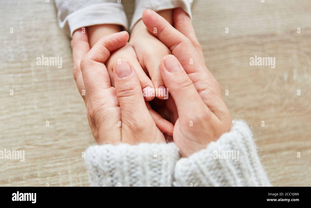Ältere Hände halten die Hände des Kindes als Trost und Zeichen Der Zuneigung Stockfoto