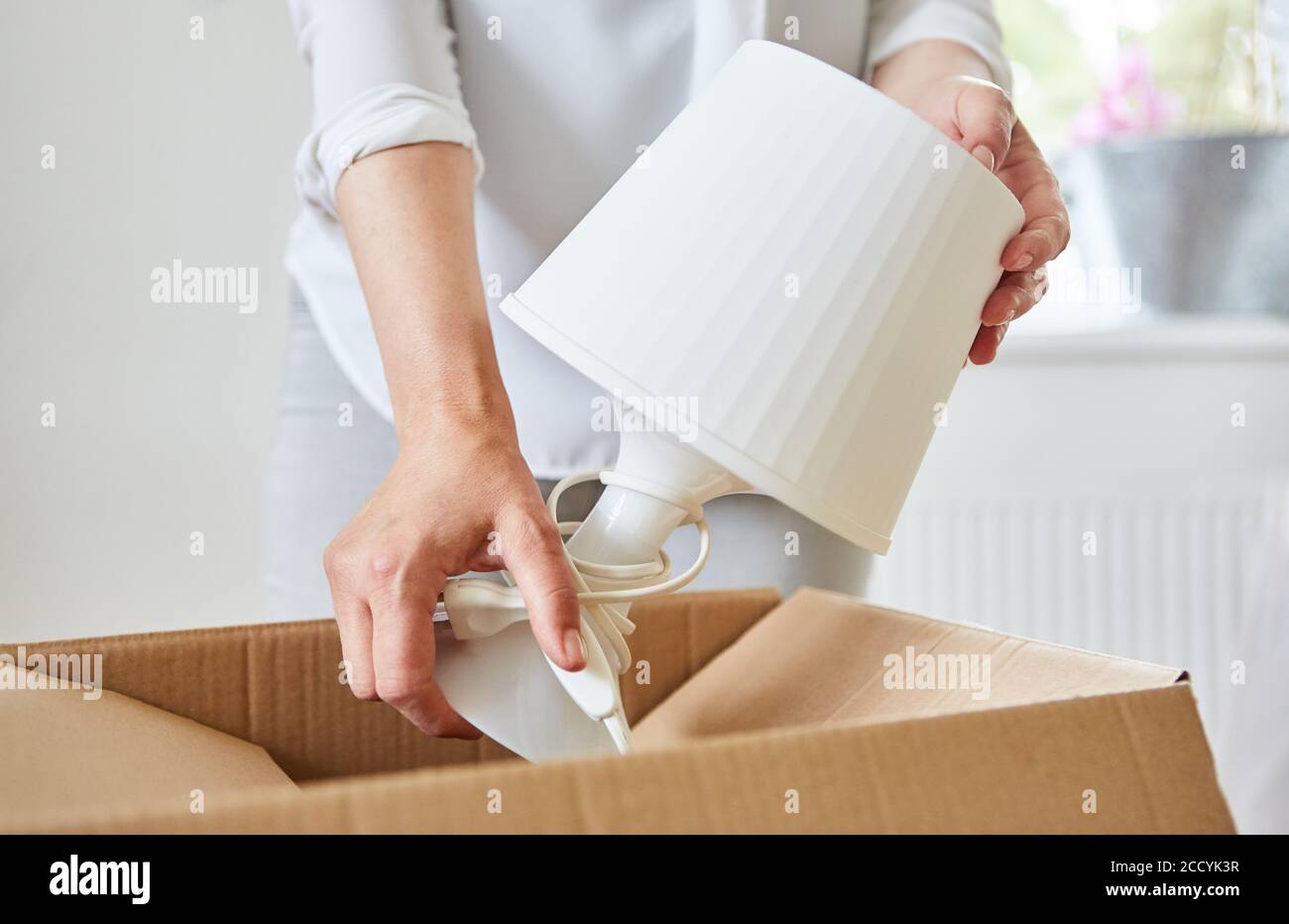 Frau packt eine Tischlampe in einem beweglichen Kasten, wenn Umzug in das neue Haus Stockfoto