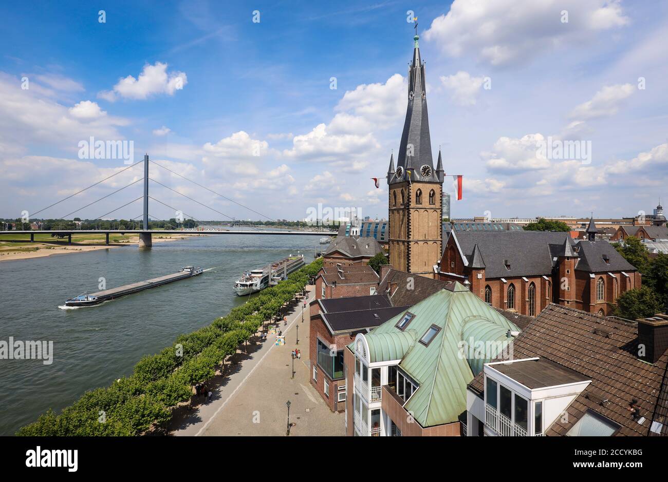 Düsseldorf, Nordrhein-Westfalen, Deutschland - Rheinpromenade mit Lambertus-Kirche, hinten ein Frachtschiff auf dem Rhein und der Oberkasseler Brücke Stockfoto