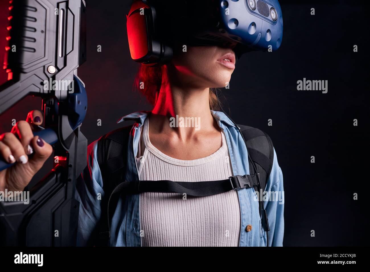 Isolierte Shoot von jungen Frau Gaming mit VR-Waffe, speacial Maske auf dem Kopf. Ultraviolett Stockfoto