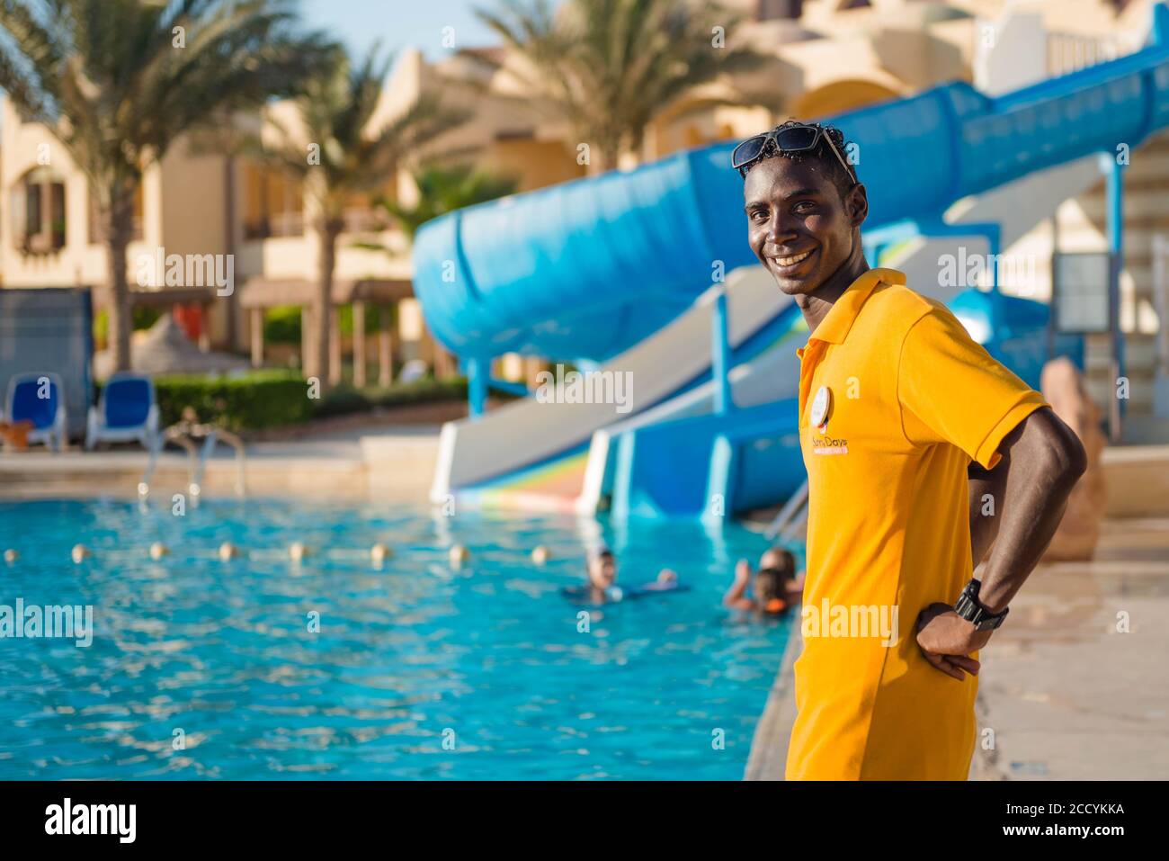 Lächelndes Porträt des ägyptischen Rettungsschwimmerers beim Schwimmen Poolbereich im Hintergrund Stockfoto