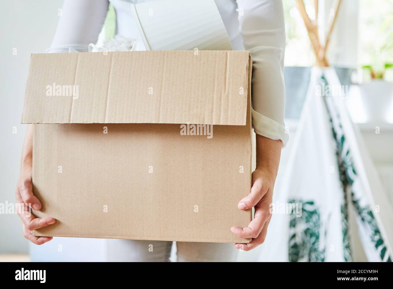 Frau trägt eine bewegliche Schachtel, wenn sie in das Neue umzieht Haus oder lästt auf Stockfoto