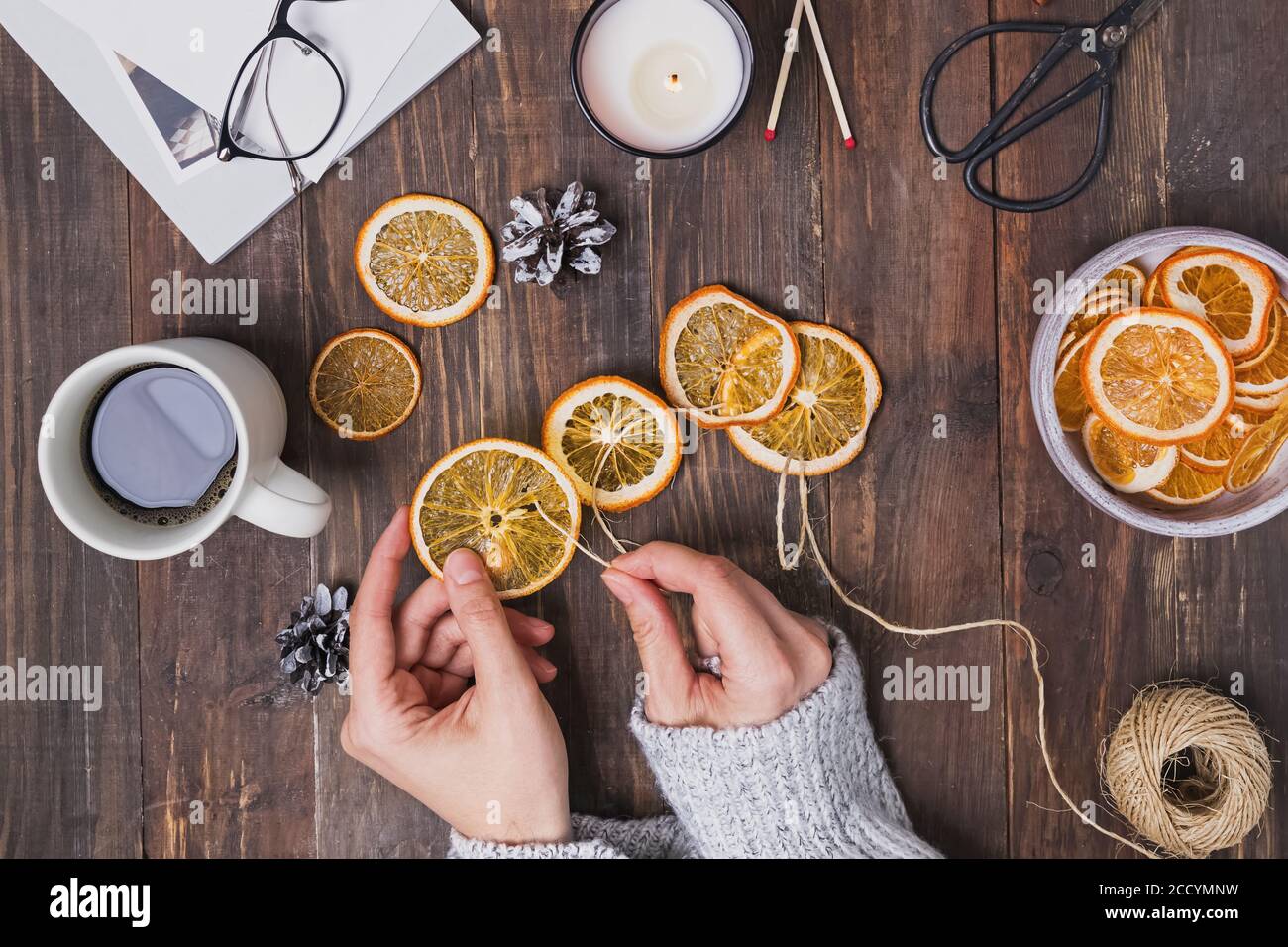 Frauen Hände machen dekorativen Kranz aus trockenen Orangen Stockfoto