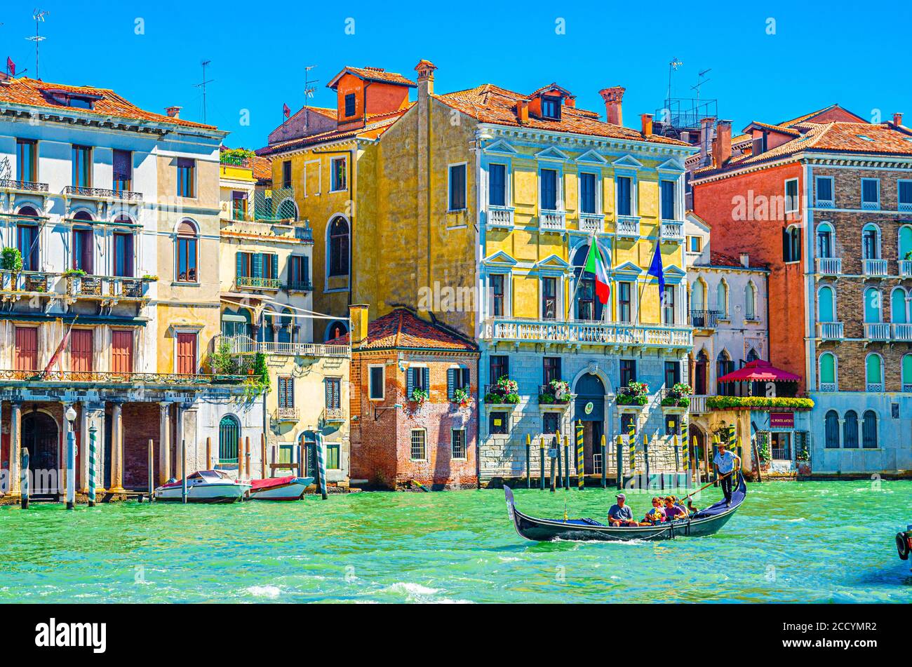 Venedig, Italien, 13. September 2019: Gondoliere und Touristen auf Gondel traditionelle Boot Segeln auf dem Wasser des Canal Grande Wasserstraße mit venezianischer Architektur typischen bunten Gebäuden Hintergrund Stockfoto