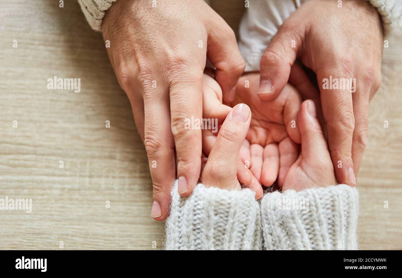 Mutter und Oma halten die Hände eines Kindes zusammen wie Ein Trost Stockfoto