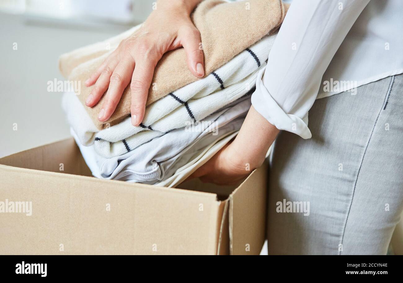 Frau packt alte Kleidung in einen beweglichen Kasten oder Leckereien Nach dem Umzug nach oben Stockfoto