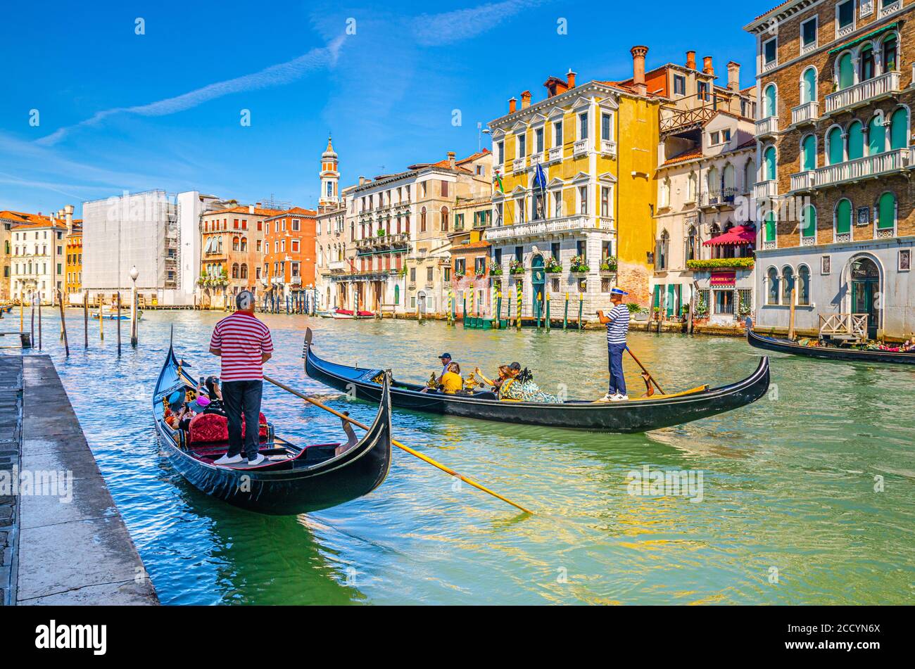 Venedig, Italien, 13. September 2019: Gondoliere und Touristen auf Gondel traditionelle Boot Segeln auf dem Wasser des Canal Grande Wasserstraße mit venezianischer Architektur typischen bunten Gebäuden Hintergrund Stockfoto