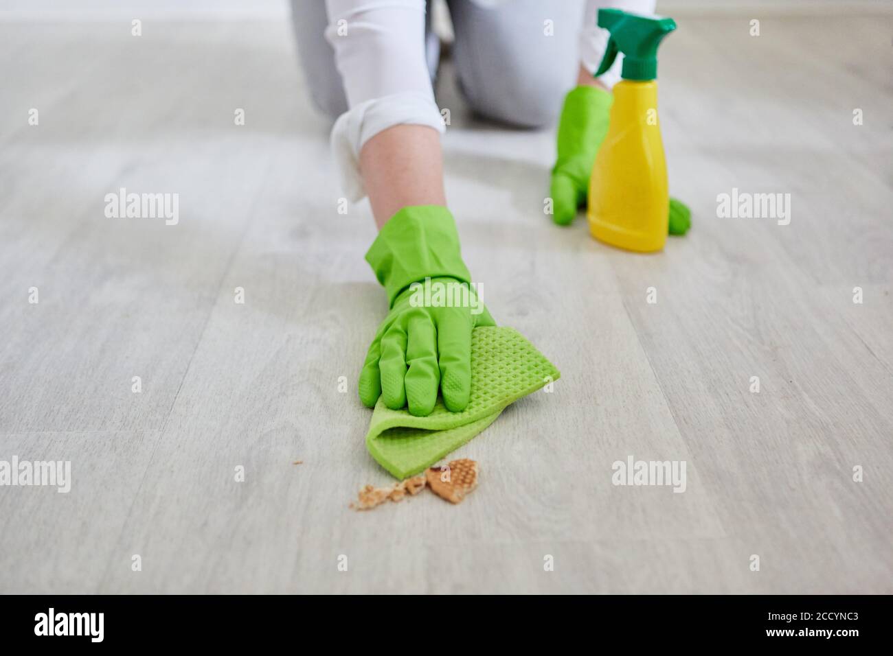 Hände mit Wischtuch wischen Krümel vom Boden während Reinigung der Küche Stockfoto