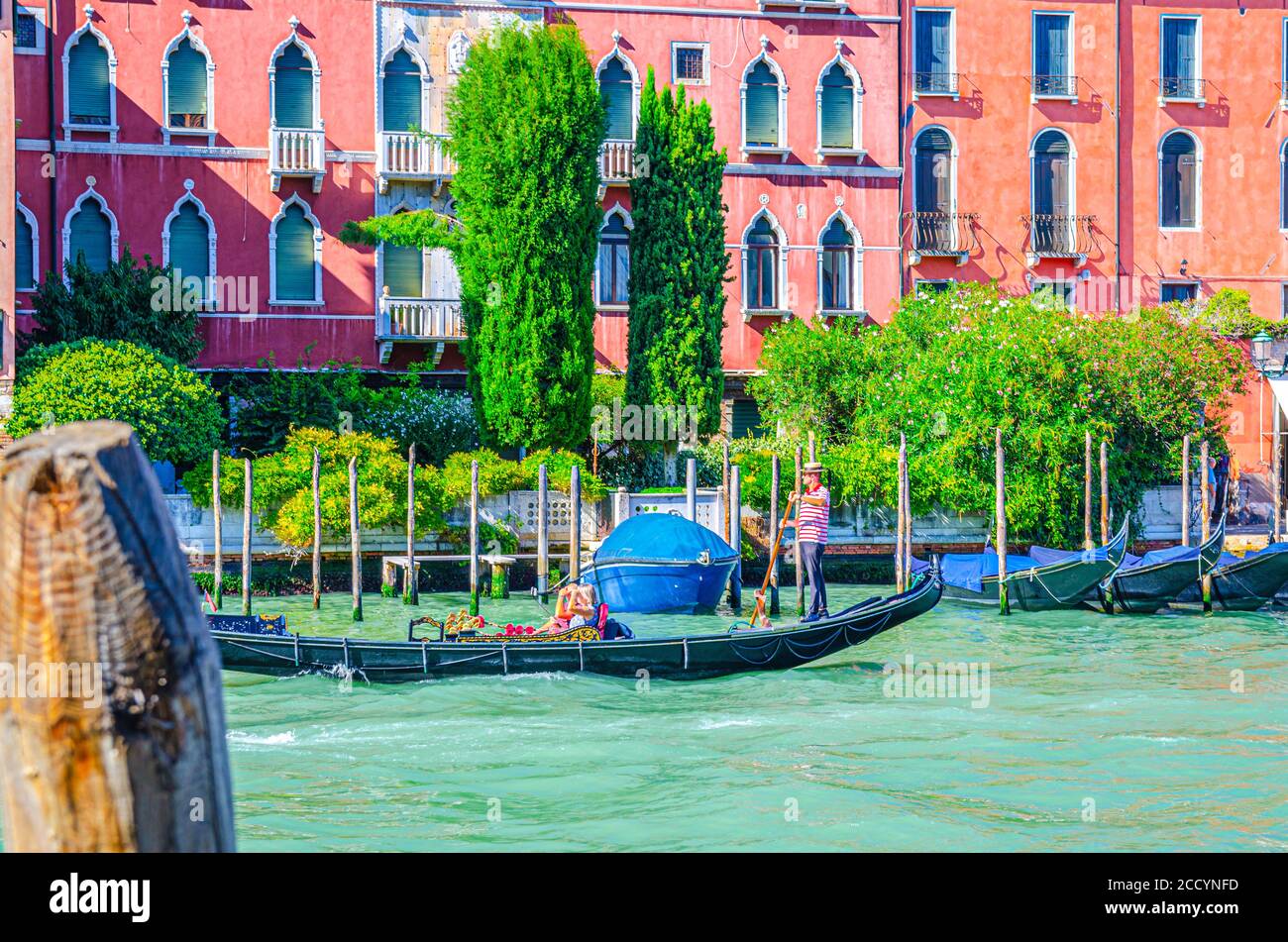 Venedig, Italien, 13. September 2019: Gondoliere und Touristen auf Gondel traditionelle Boot Segeln auf dem Wasser des Canal Grande Wasserstraße mit venezianischer Architektur typischen bunten Gebäuden Hintergrund Stockfoto
