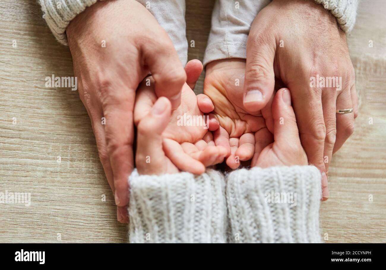 Senioren Hände halten die Hände eines Kindes als ein Symbol der Liebe und des Trostes Stockfoto