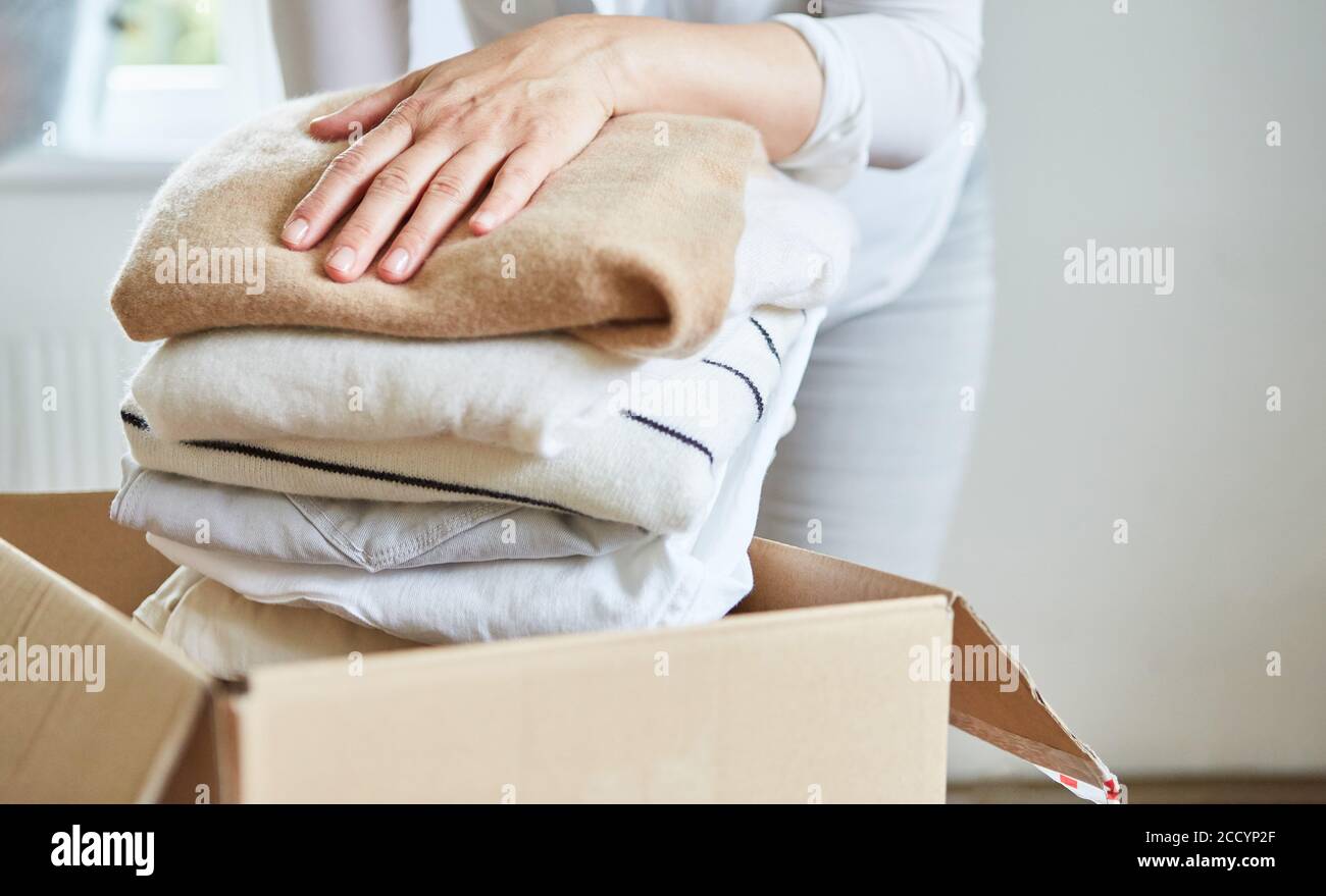 Frau packt Kleidung für eine Kleiderspende in eine Box Oder aufgibt Stockfoto