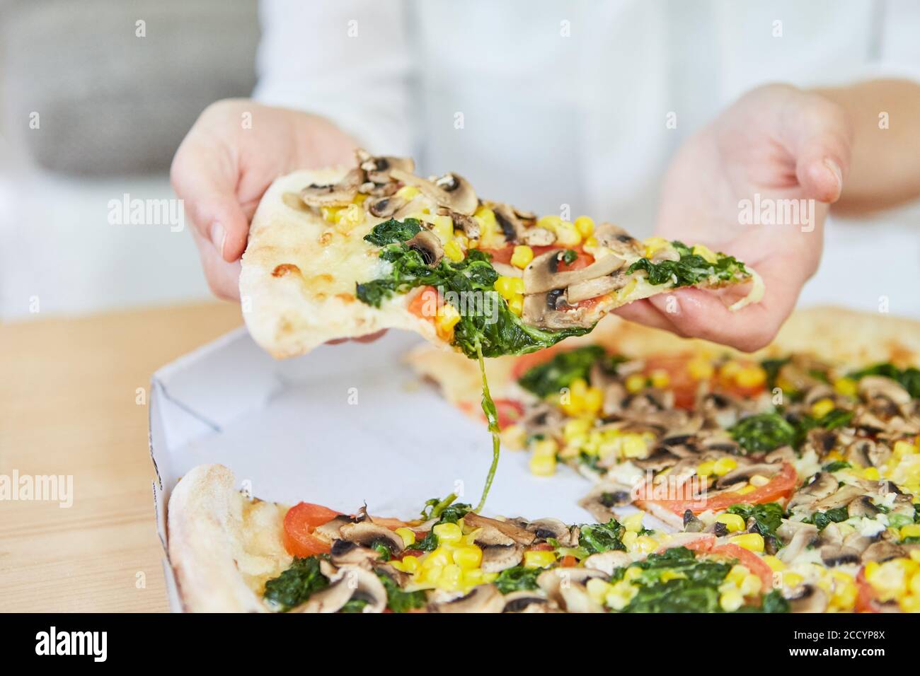 Hand mit Scheibe Pizza beim Essen einer Gemüse-Pizza Als veganes Mittagessen Stockfoto