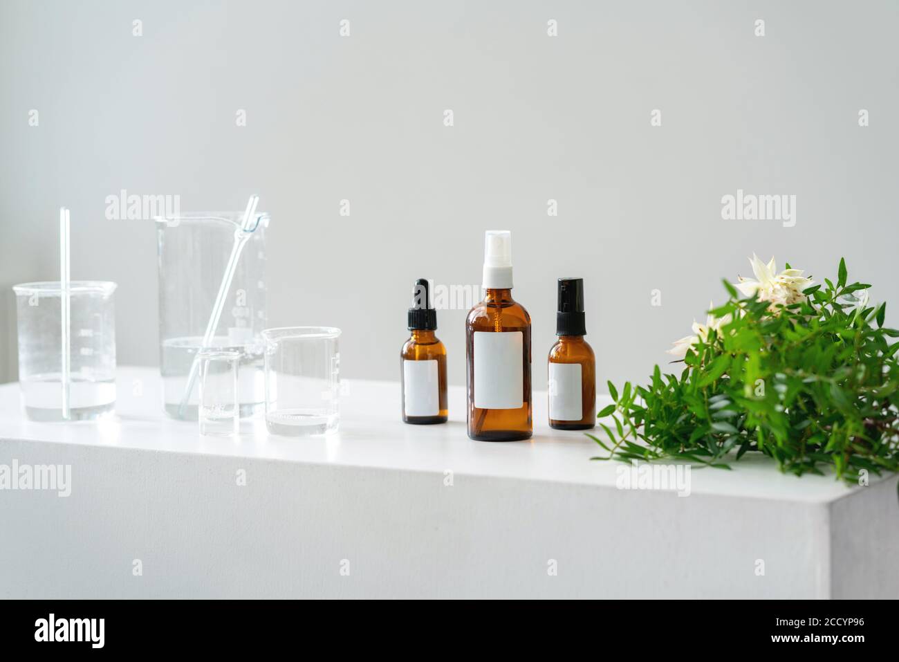 Heller kosmetischer Hintergrund. Fläschchen, Laborflaschen aus Glas auf dem Tisch. Naturkosmetik-Konzept. Stockfoto