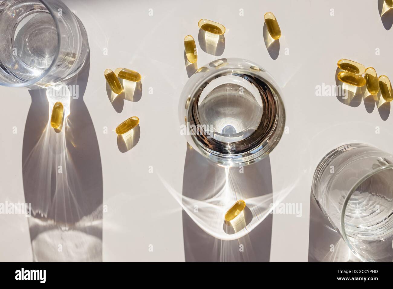 Omega 3 Kapseln und Gläser mit Wasser auf weißem Tisch. Stockfoto