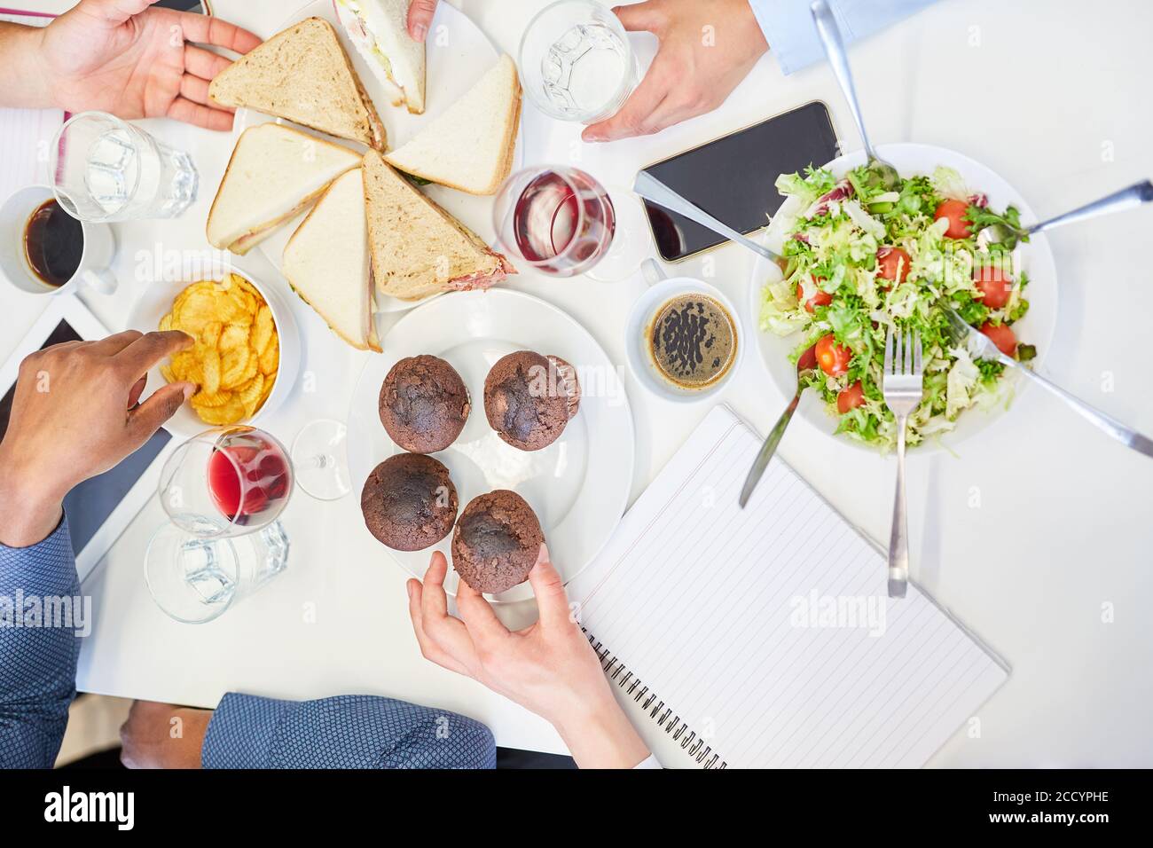 Kollegen essen Muffins und Sandwiches als Snack zusammen Im Büro Stockfoto