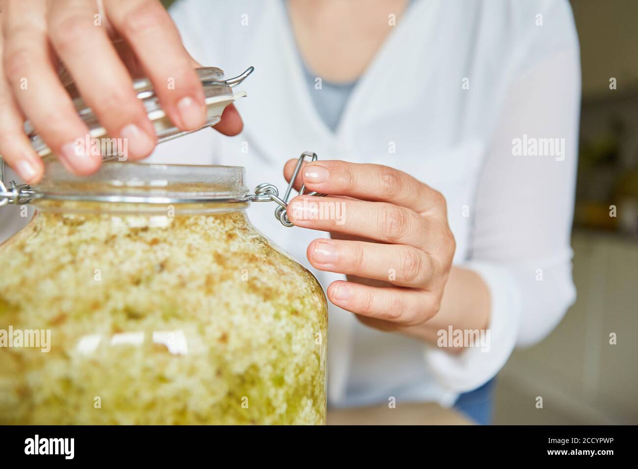 Hausfrau schließt den Deckel eines Einmachglas mit eingelegtem Holunderblüte Stockfoto