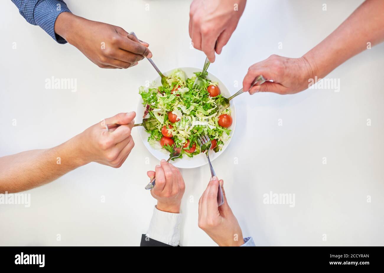 Hände mit Gabeln beim Essen Salat zusammen für vegetarische Ernährung Im Büro Stockfoto