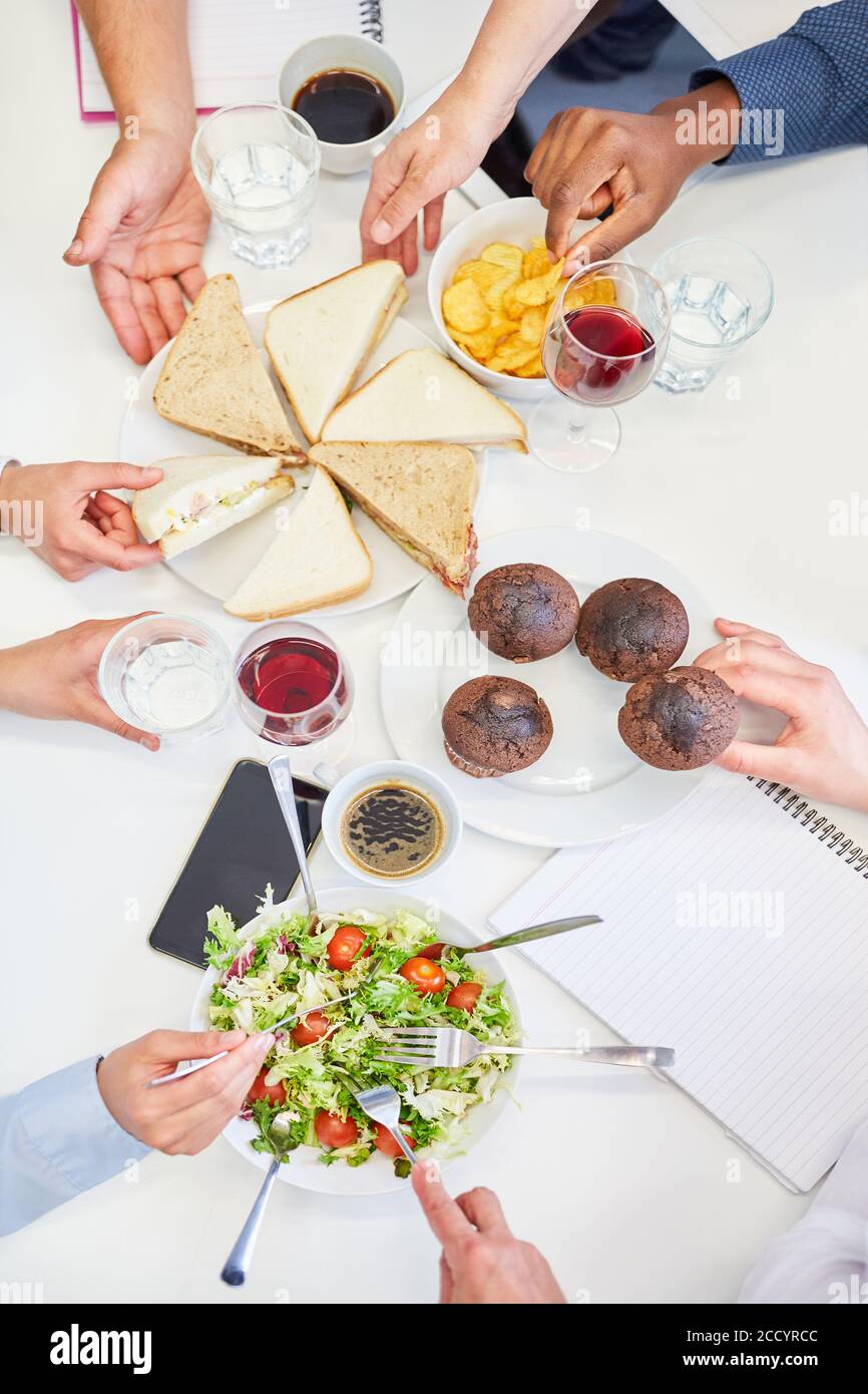 Geschäftsleute essen Sandwich und Muffin zusammen als Snack während Eine Büropause Stockfoto