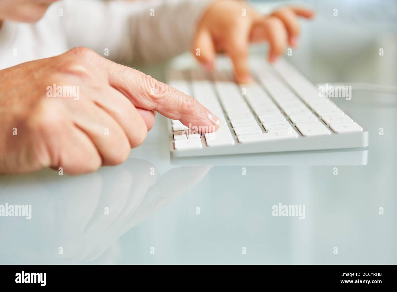 Hand von älteren Frau und Kind zusammen auf Computer-Tastatur Stockfoto