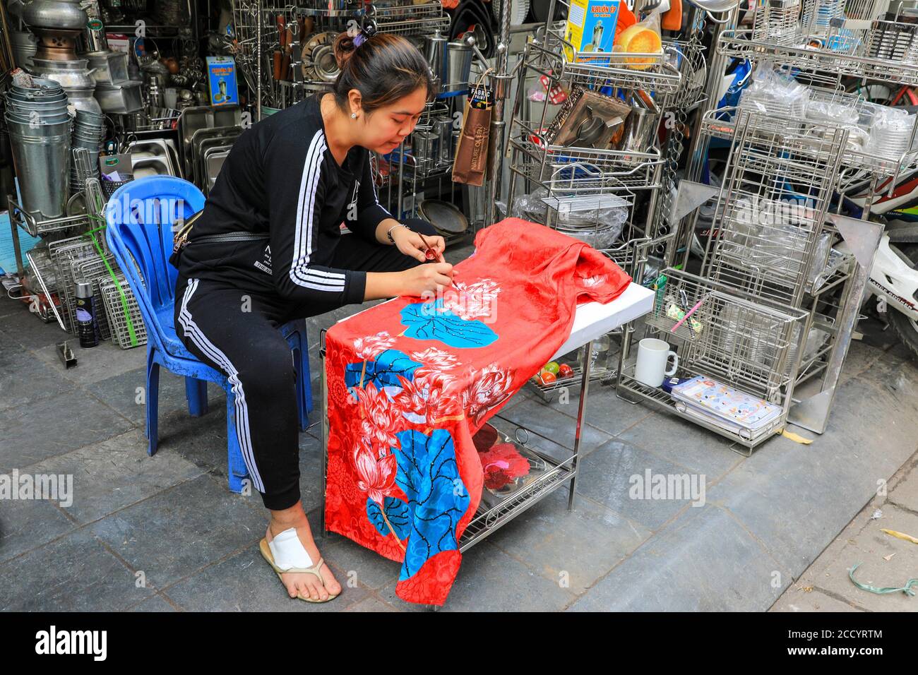 Eine Schneiderin, die ein traditionelles vietnamesisches Kleid namens AO dai vor einem Geschäft auf der Straße in Hanoi, Vietnam, Asien, herstellte und dekorierte Stockfoto